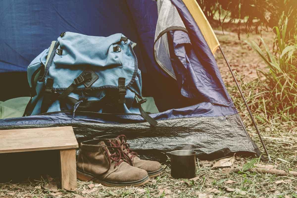 prikaz kamp šatora, ranca, cipela i lončića metalnog
